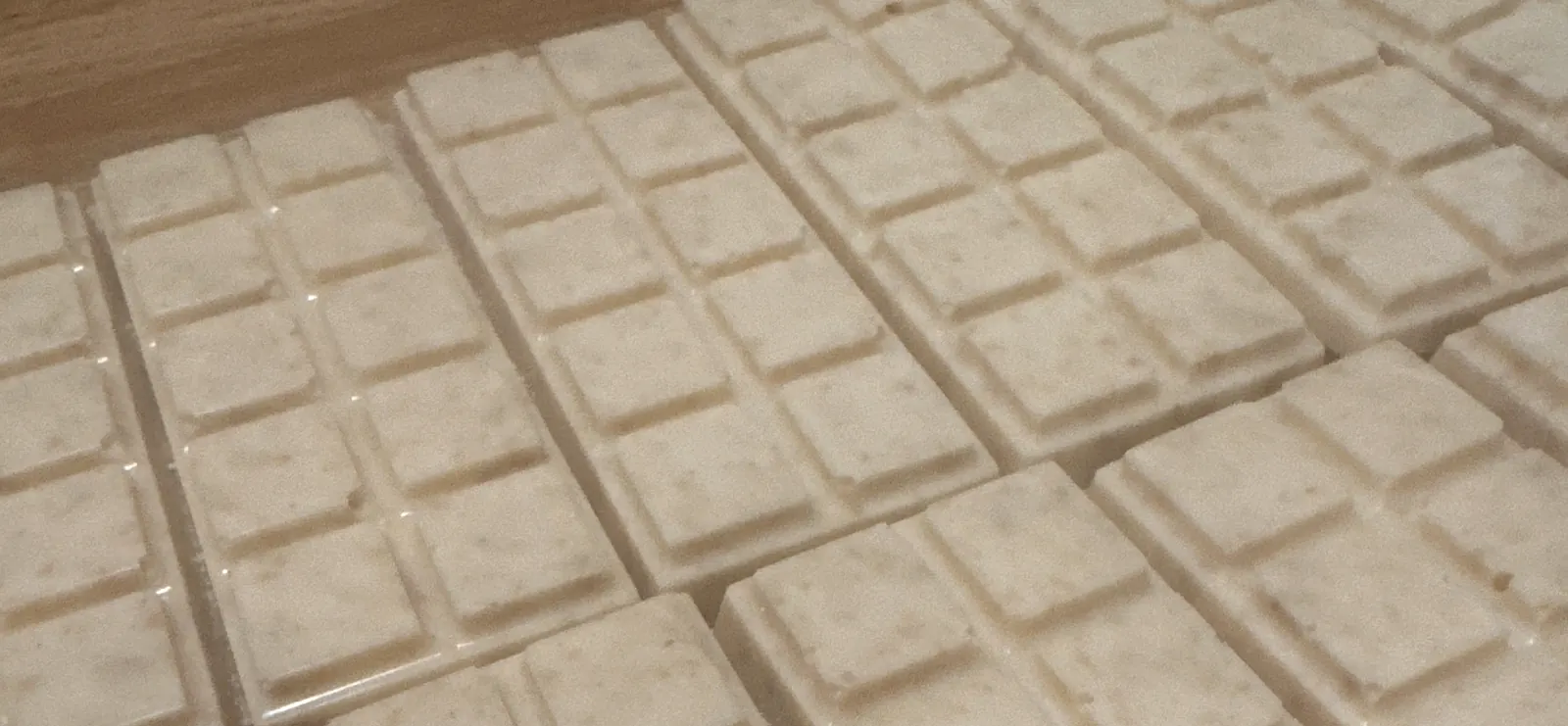 Trays of freshly poured Huckle Buck's candy bars, all the same cream color, flecked with graham cracker cereal